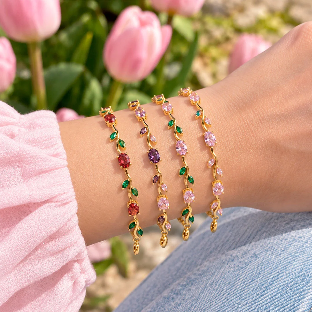Cuatro pulseras de tulipanes con baño de oro en la muñeca, con tulipanes rosados de fondo